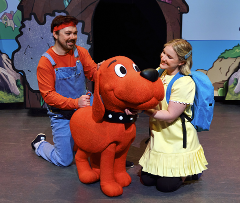 A young girl kneeling beside Clifford the Big Red Dog